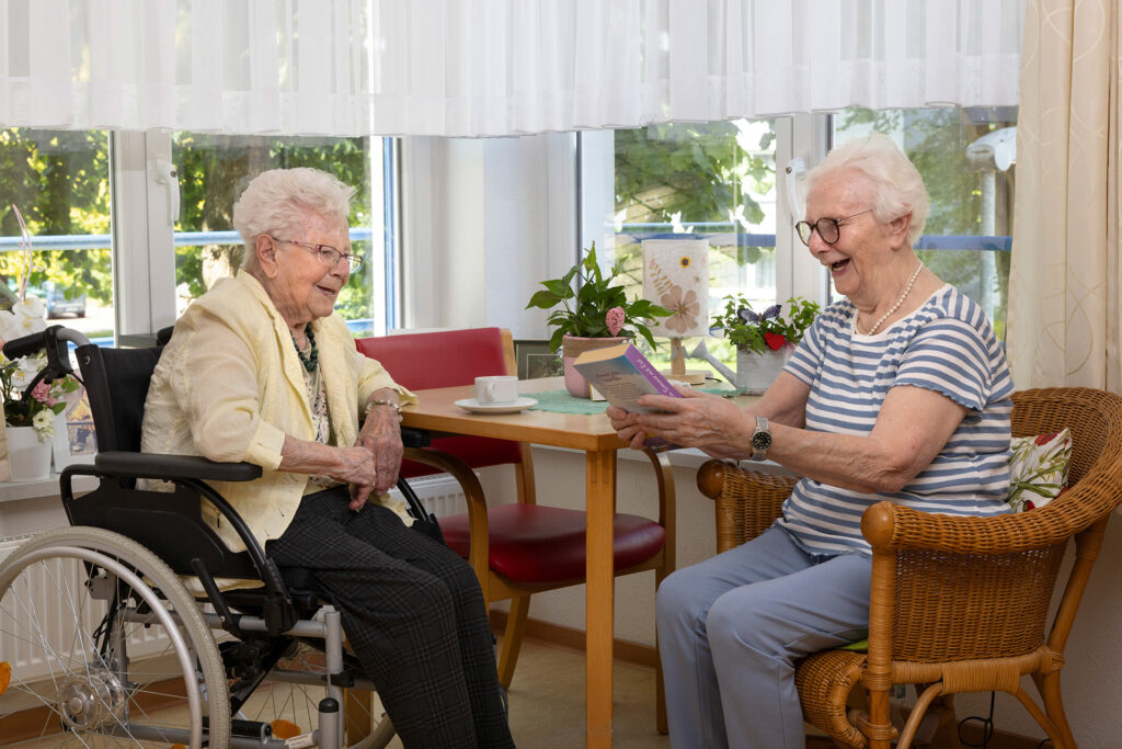 Zwei Bewohnerinnen sind im Gespräch über ein Buch.