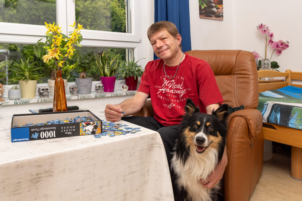 Ein Bewohner legt ein Puzzle. Bei ihm sitzt sein Hund.