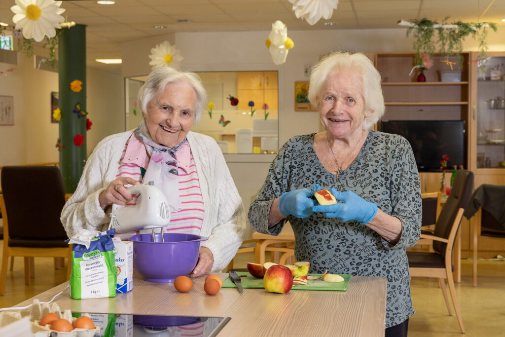 Zwei Bewohnerinnen backen gemeinsam einen Apfelkuchen.