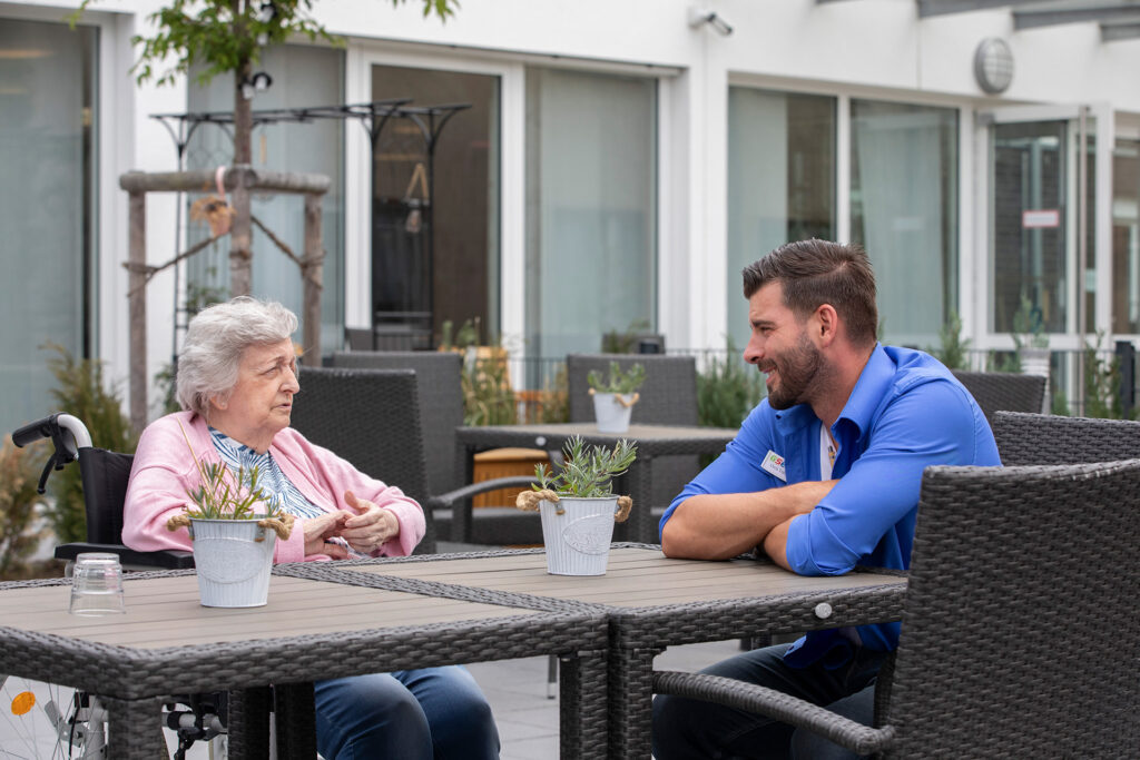 Eine Bewohnerin ist mit Einrichtungsleiter Chris Trostmann auf der großen Sonnen-Terrasse im Gespräch.