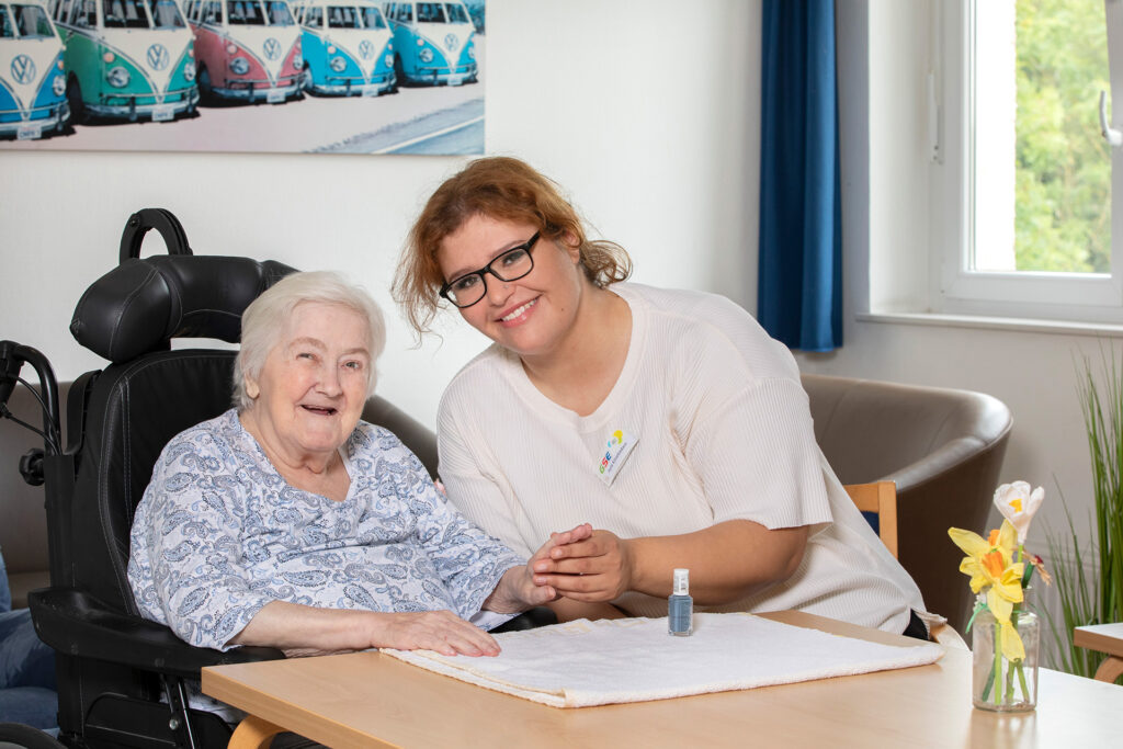 Eine Mitarbeiterin lackiert einer Bewohnerin die Fingernägel.