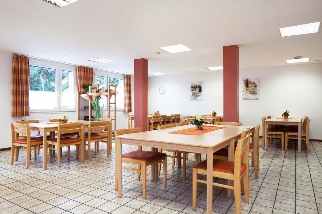 Im Speiseraum des Wohnheims Esternhovede stehen mehrere Tischgruppen. Durch große Fenster fällt viel Tageslicht in den Raum.