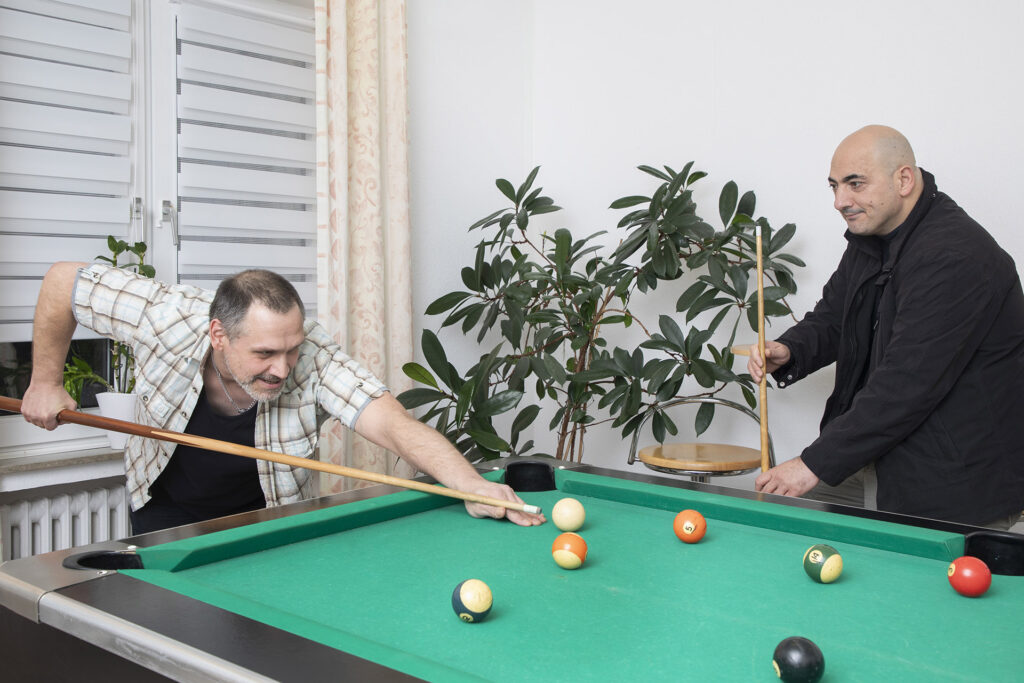 Zwei Bewohner spielen Billard am Billardtisch im Männerwohnheim Stoppenberg.
