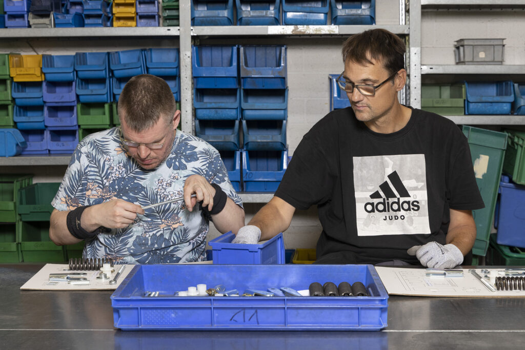 Zwei Werkstattmitarbeiter stellen konzentiert ein Set für die weitere Verpackung zusammen.