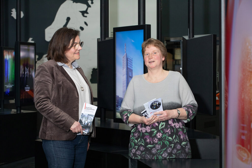 Eine Mitarbeiterin, die im Museum arbeitet, ist mit einer Besucherin im Gespräch.